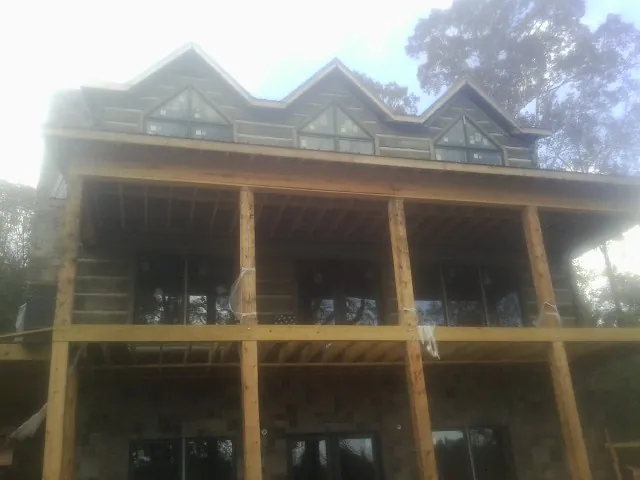 Dormers and porch framing on a large log home under construction — Roof Coating work by our crew in Easton