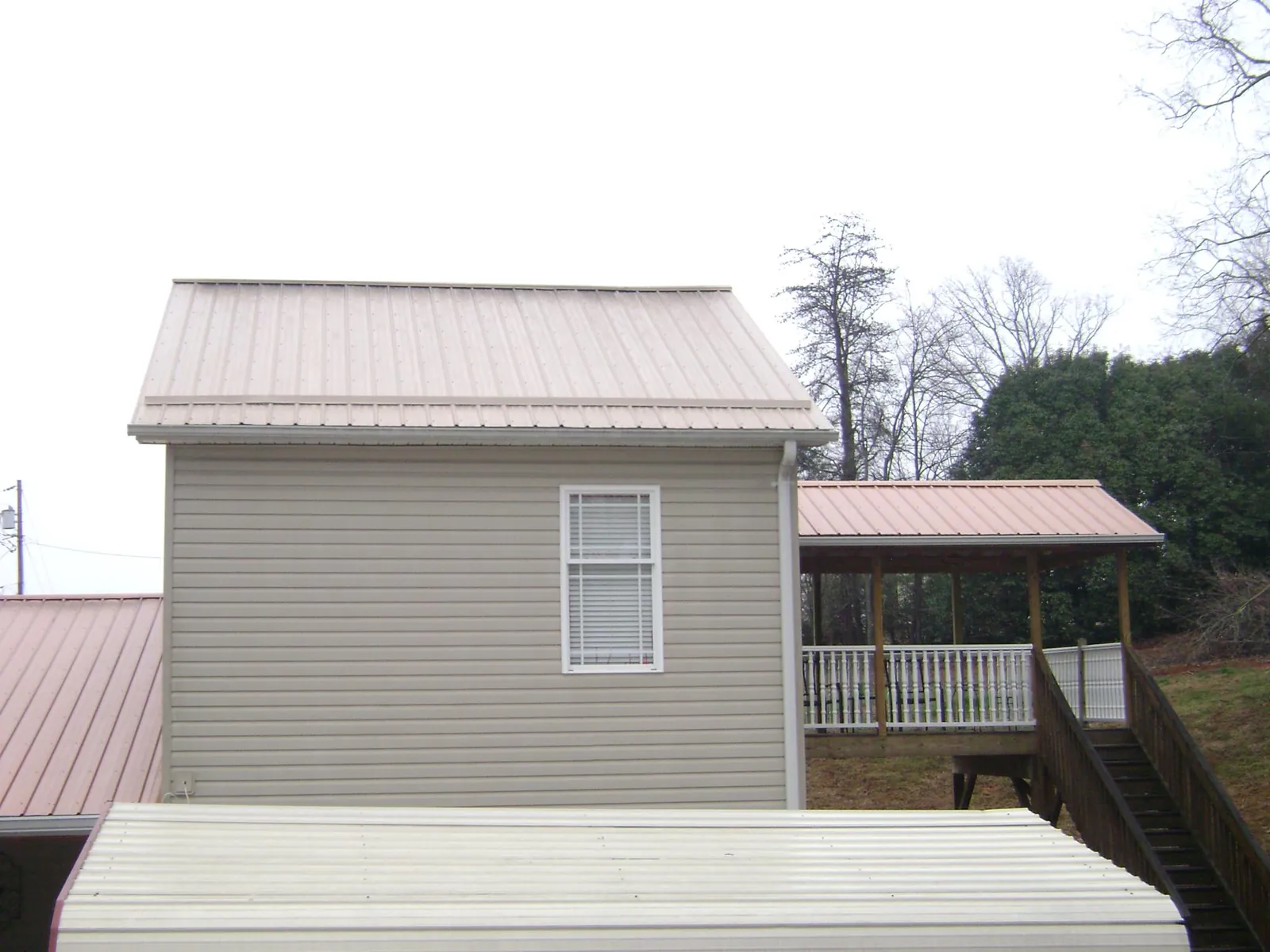 Tan metal roofs on a two story addition and attached porch, from a Roof Replacement job in Easton